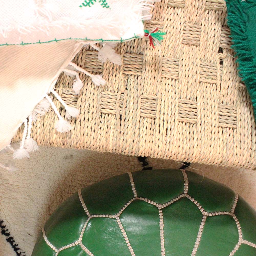 Green leather pouf and woven home decor arranged on a textured Moroccan textile