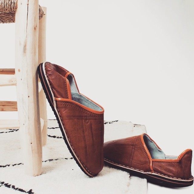Brown and black leather babouches photographed in a bright architectural setting