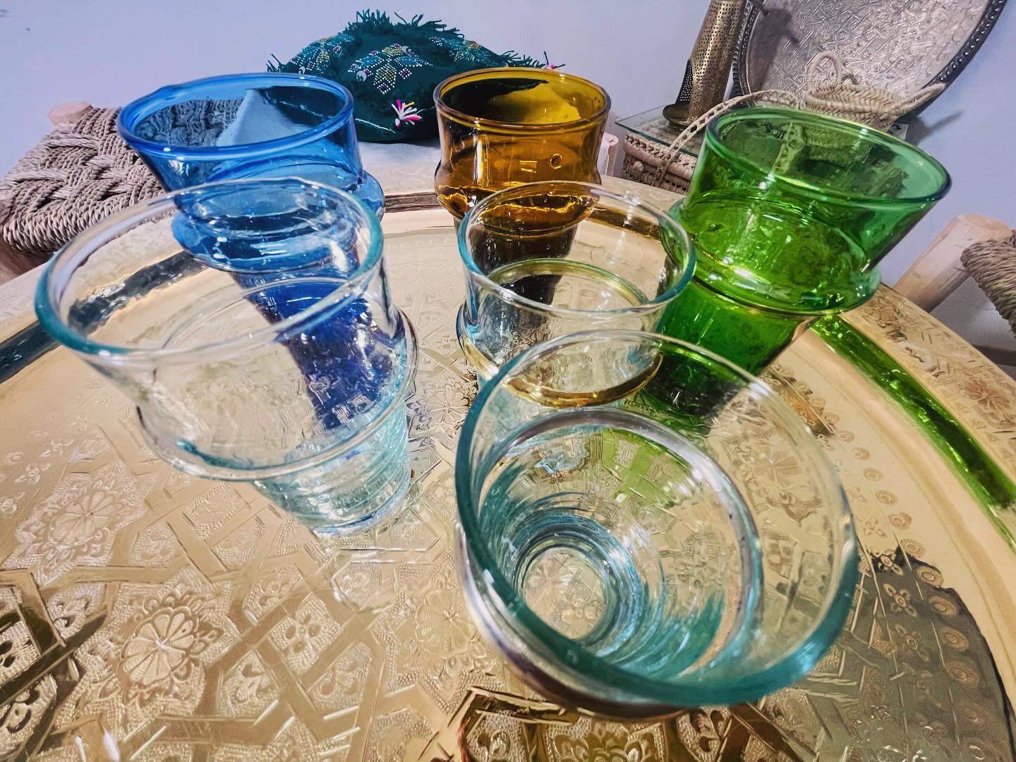 Multicoloured handblown Moroccan Beldi glasses arranged on a metal tray outdoors