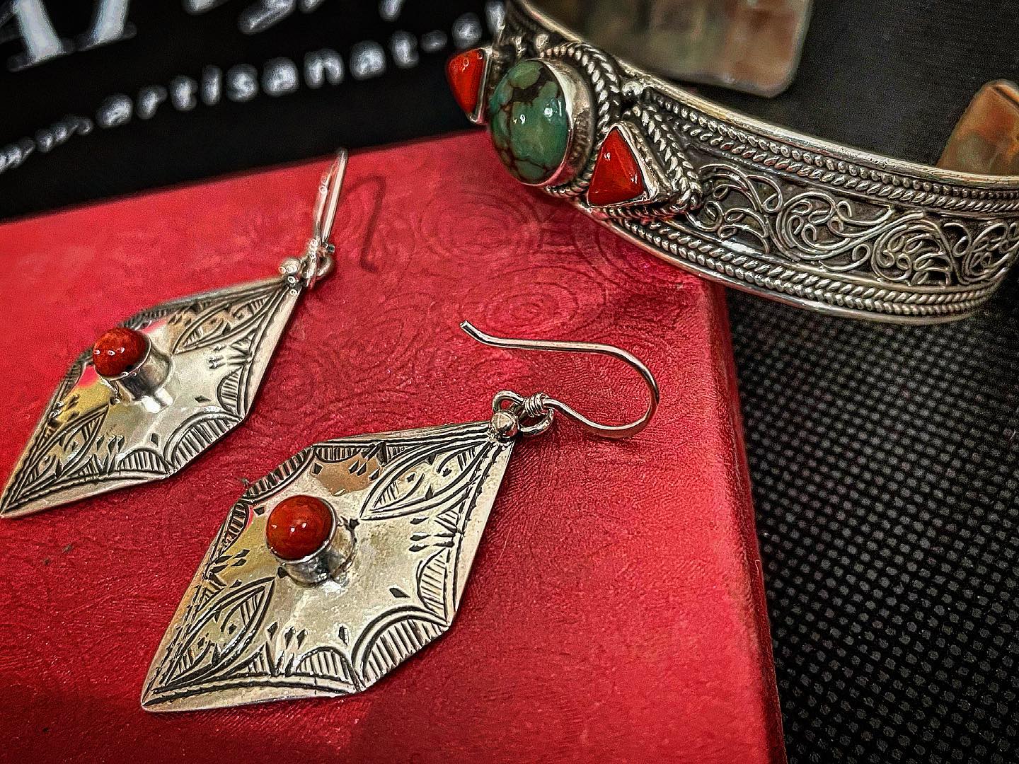 Berber silver jewellery with red and green stones arranged on red and black textiles